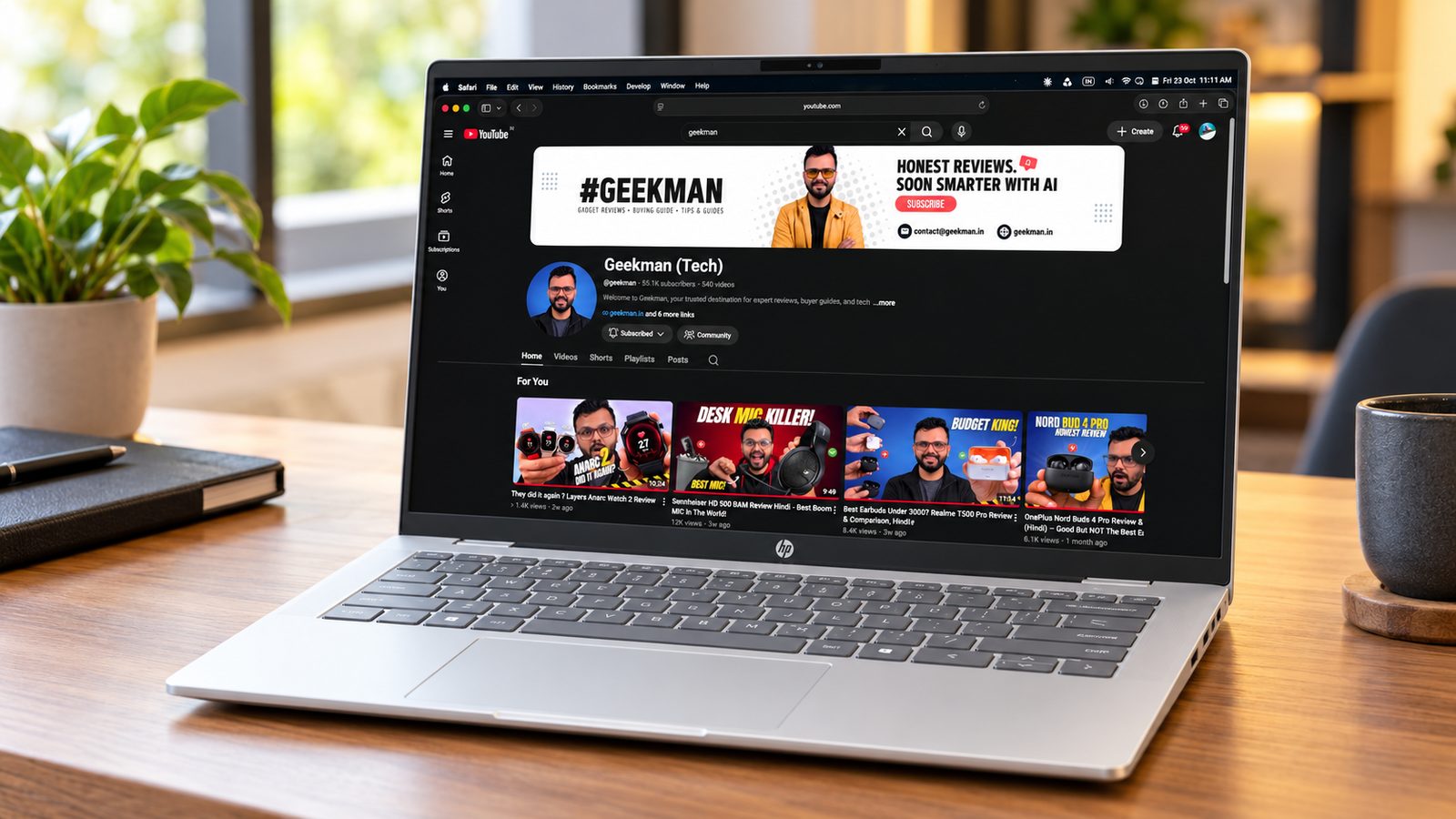 HP OmniBook 5 14 OLED laptop on a wooden desk with the Geekman channel on screen